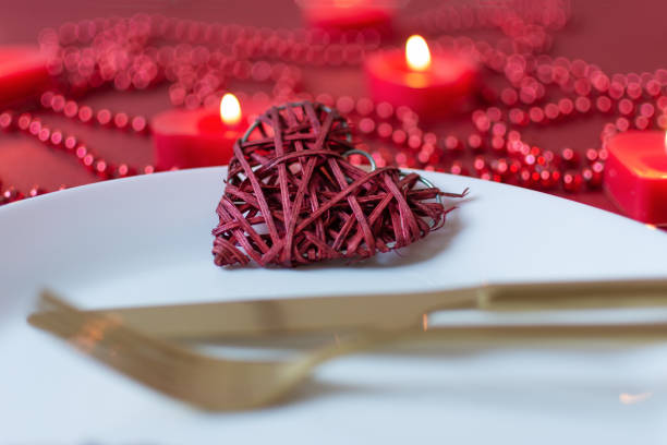 Serving table with fork, knife, napkin and heart decoration for Valentine's . Dinner table in red colors on Valentines day. Top view.