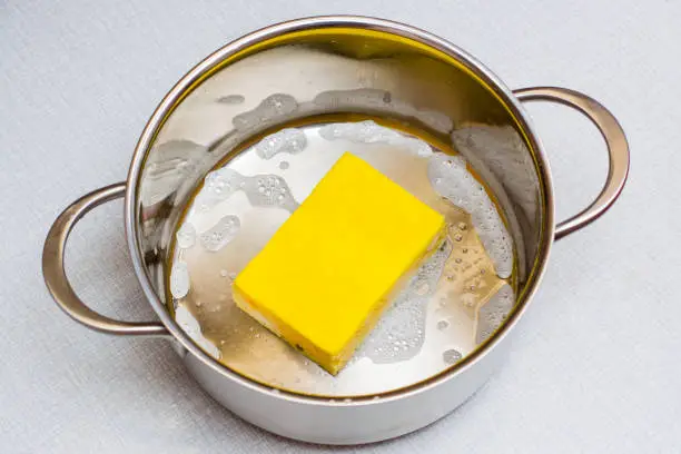 Photo of The yellow dishwashing sponge lies at the bottom of the soaped pan