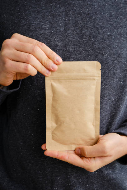 istock Kraft paper packaging in a mans hands. Packaging for coffee, cosmetics. Packing closeup. Product for sale. Online shopping. Boxes with surprise. Delivery service, shipping. Empty, mockup. Eco friendly 1189403158