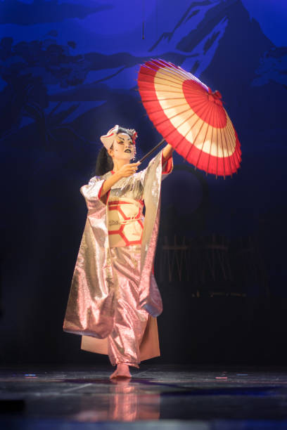 istock Traditional Japanese performance. Actress in traditional kimono and fox mark dancing with umbrella. 1189405331