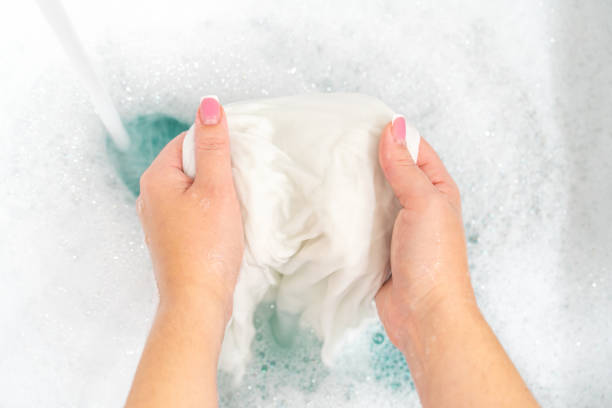 istock Hand washing white clothes in sink to bleach 1189415998