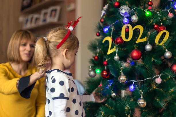 Cute girl decorating Christmas tree Woman observing daughter decorating Christmas tree фоп 2 група 2022 stock pictures, royalty-free photos & images
