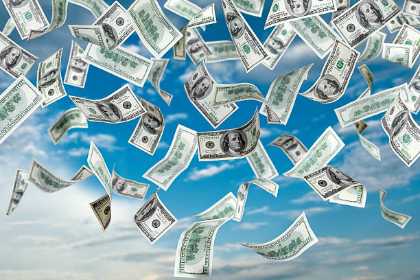 One hundred dollar bills falling out of the sky stock photo