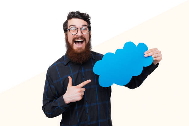 istock Haapy bearded guy, wearing glasses is pointing at bubble speech and looking at camera over white background 1189421126