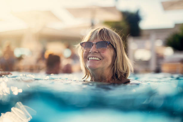 retrato de una mujer feliz mayor disfrutando de la piscina - recreational pursuit leisure activity relaxation fun fotografías e imágenes de stock