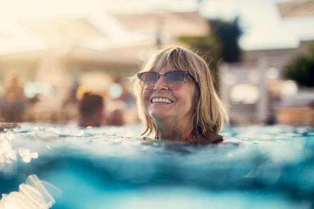 портрет счастливой старшей женщины, наслаждаясь бассейном - senior adult outdoors wellbeing sky стоковые фото и изображения