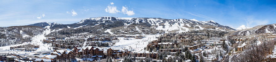 High resolution panorama with many photos stitched together to create a wide view of the entire Snowmass Mountain Ski Resort of Aspen, Colorado. Ski lifts, resorts, and town with ski runs.