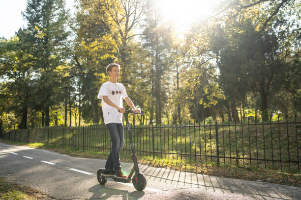 istock Boy riding push scooter in park 1189444905