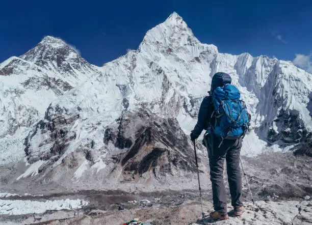 Young hiker backpacker female taking brake in hike walking enjoying Khumbu Glacier. Everest Base Camp route near Gorakshep,Nepal. Everest mount 8848m (left) and Nuptse 7861m (right) on background.