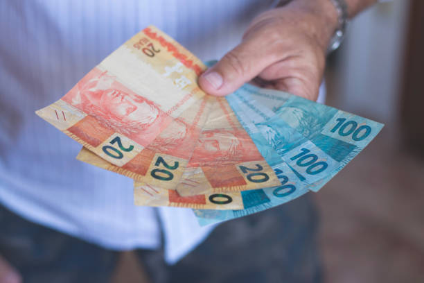 istock Man holding Brazilian money banknotes with his hands 1189457376