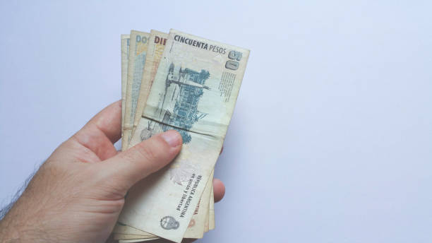 istock Hand holding argentinian money banknote with white background 1189457384