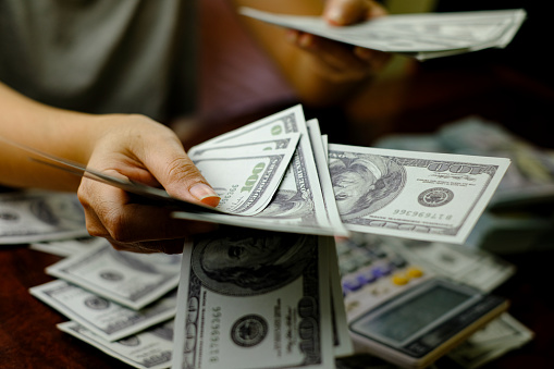 Hombres de negocios mujeres contando dinero en una pila de 100 dólares estadounidenses billetes de un montón de dinero photo