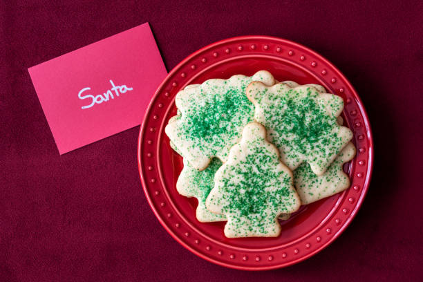 Christmas Cheer Christmas sugar cookies for Santa on a red plate, note to Santa, red fabric background round sugar cookie stock pictures, royalty-free photos & images