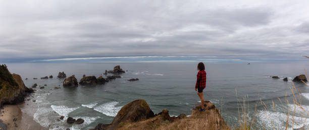 fille aventureuse restant à la falaise rocheuse sur la côte de l'océan pacifique - oregon beach photos et images de collection