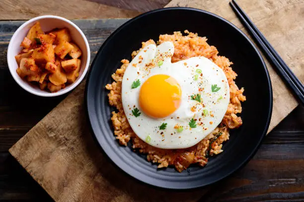 Kimchi fried rice with fried egg on top and fresh radish kimchi, Korean food, top view
