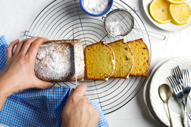 レモンパウンドケーキ。焼きたてのレモンパウンドケーキを切る女性のトップビュー - bread bakery women cake ストックフォトと画像