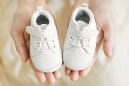 Tiny white baby shoes in man