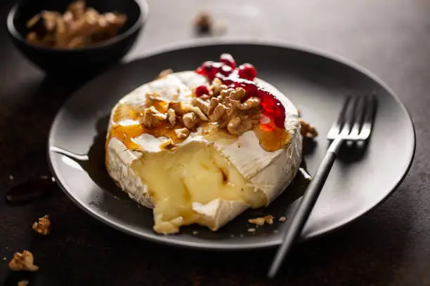 Closeup of tasty baked camembert with nuts and cranberries.