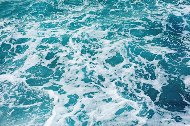 istock Turquoise sea surface background with splashing waves 1189478433