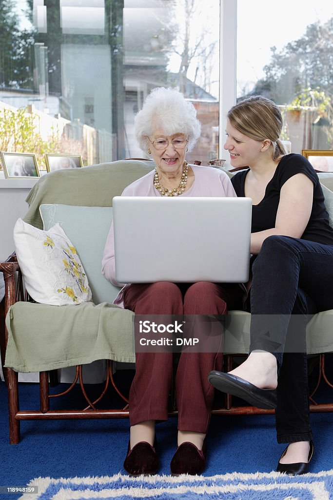 Jovem e sua avó, a trabalhar no computador portátil em casa - Royalty-free Adulto Foto de stock
