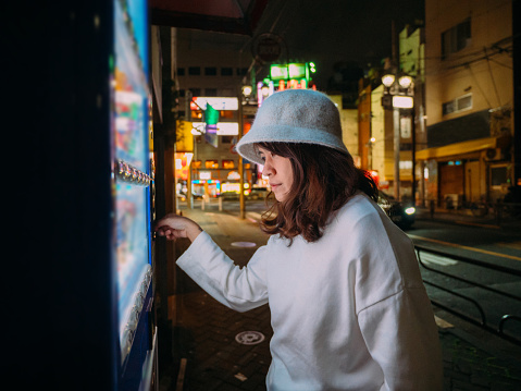 Young women Buying some drink from Vending Machine in Japan.