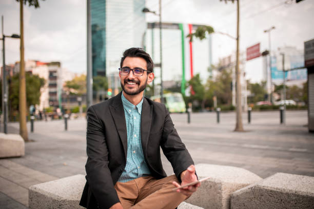 istock Young businessman sitting outside and using the phone 1189487286