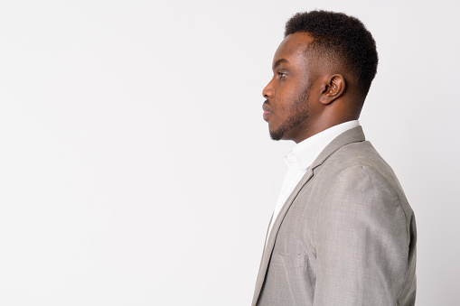 Studio shot of young African businessman wearing suit against white background