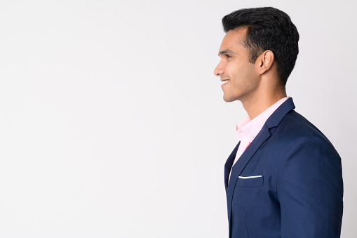 Studio shot of young handsome Indian businessman wearing suit against white background