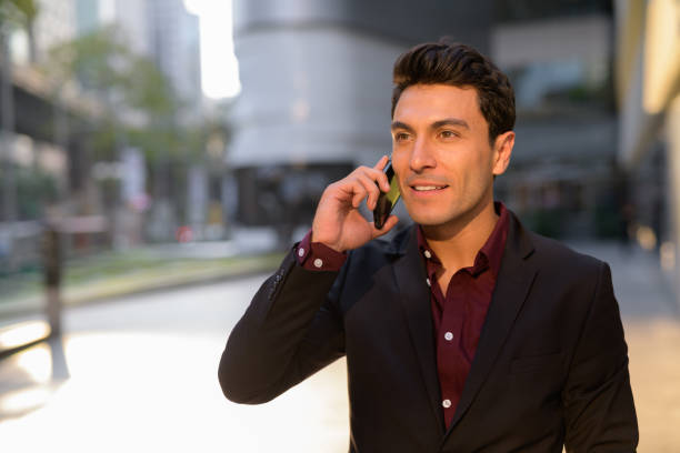 istock Happy young Hispanic businessman thinking while talking on the phone outdoors 1189491285