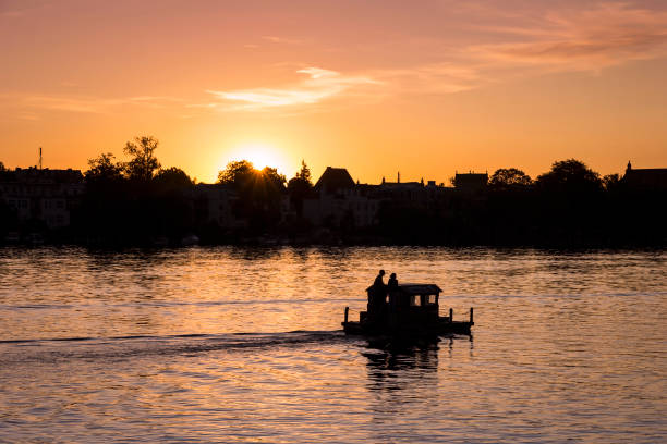 View on a very romantic part of the city Potsdam, small boat swimming on the Havel View on a very romantic part of the city Potsdam, small boat swimming on the Havel, towards the sunset, in the state Brandenburg, Germany. potsdam brandenburg stock pictures, royalty-free photos & images