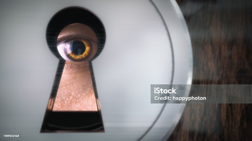 A man looks through a keyhole. Close-up. A man looks through a keyhole. Close-up Keyhole Stock Photo