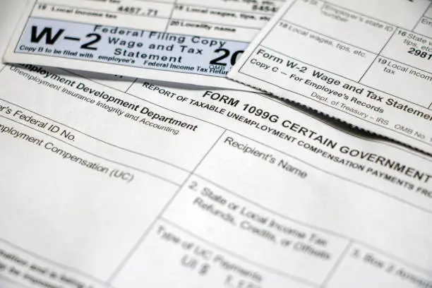 Closeup of Form 1099G Certain Government Payouts with W-2 forms overlapping on top.