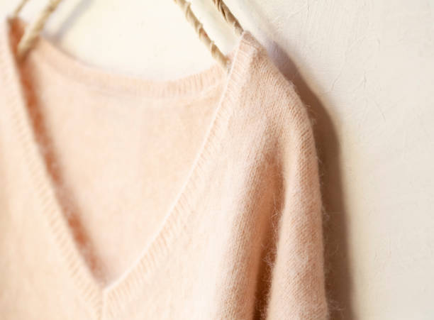 istock light pink sweater hanging on clothes hanger on white background. 1189507416
