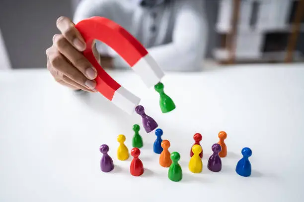 Photo of Businessperson Attracting Pawn Figures With Horseshoe Magnet