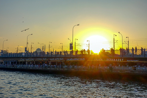 Istanbul, Turkey - October 15, 2019; People fishing on Galata bridge at sunset.