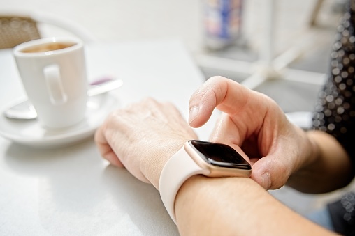 A businesswoman looks at her smart watch to check notifications during a coffee break