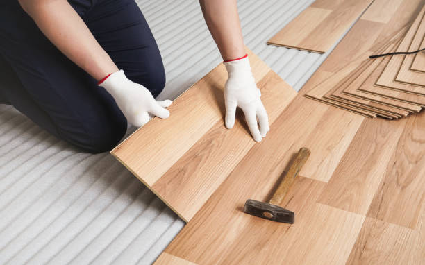 istock Man installing laminated floor, detail on wooden tile being fitted, over white foam base layer 1189521162