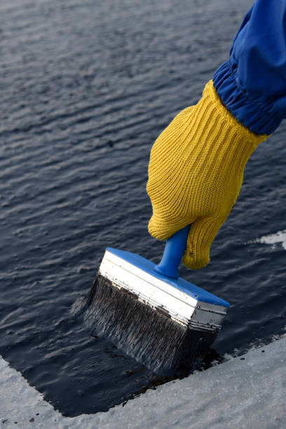 worker applies bitumen mastic on the foundation - bitumen felt imagens e fotografias de stock