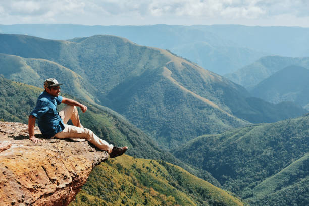 istock Man Looking at valley views while sitting on the cliff 1189532888