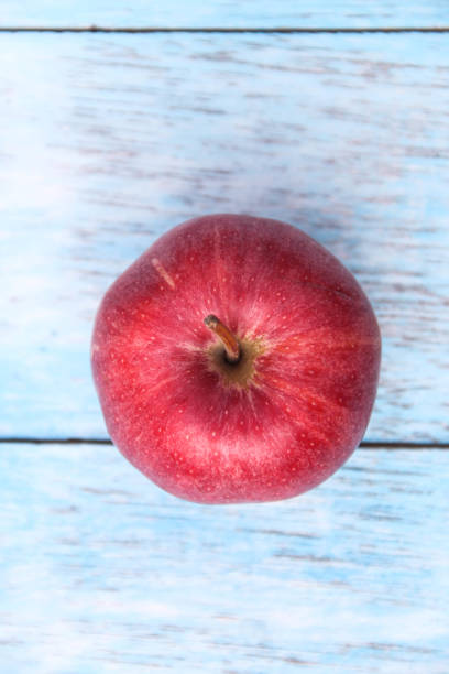 Manzana orgánica roja fresca sobre tablero de madera azul. El color rojo representa la Navidad y la celebración. - foto de stock