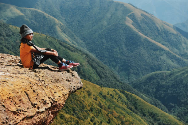 istock Girl looking at valley views while Sitting on the cliff 1189533662