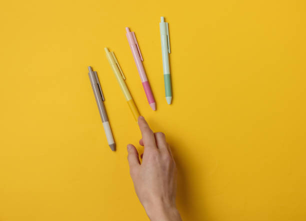 istock Female hand selects pen on yellow background. Top view 1189535981