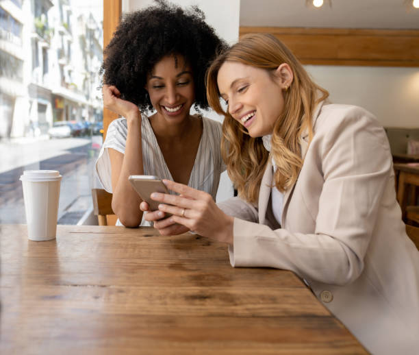 istock Diverse white collar workers taking a break laughing while looking at something on smartphone in a coffee shop 1189537899