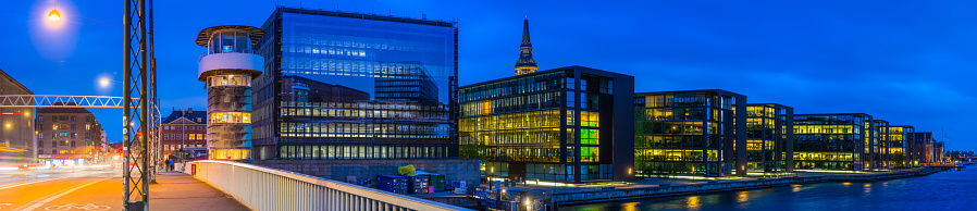 Panoramic view at night across the famous Knipples Bridge to the modern office buildings, hotels, apartment buildings and bridges that line the harbour waterfront in central Copenhagen, Denmark’s vibrant capital city.
