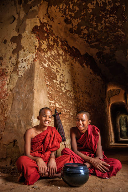 начинающие буддийские монахи, созерцающие внутри храма, мьянма - buddhism monk book zen like стоковые фото и изображения