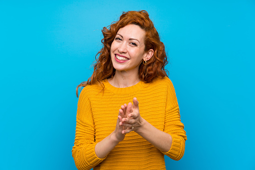 Redhead woman with yellow sweater applauding after presentation in a conference