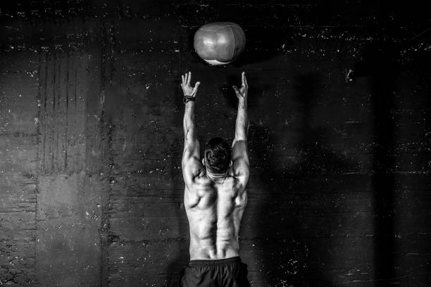 молодые сильные потные сосредоточены подходят мускулистый человек с большими мышцами делать бросали медицины мяч на стене для перекрестн� - determination 20s adult attractive male стоковые фото и изображения