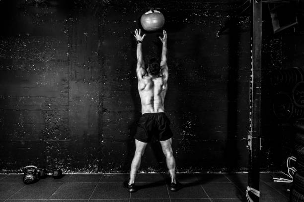 젊은 강한 땀이 맞는 근육 남자 와 큰 근육 을 던지는 약 공을 벽에 대 한 크로스 트레이닝 하드 코어 운동 에 체육관 실제 사람들 선택적 초점 흑백 - body building weight training men flexing muscles 뉴스 사진 이미지