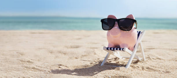 pink piggybank auf deck stuhl über dem sandstrand - 401k stock-fotos und bilder