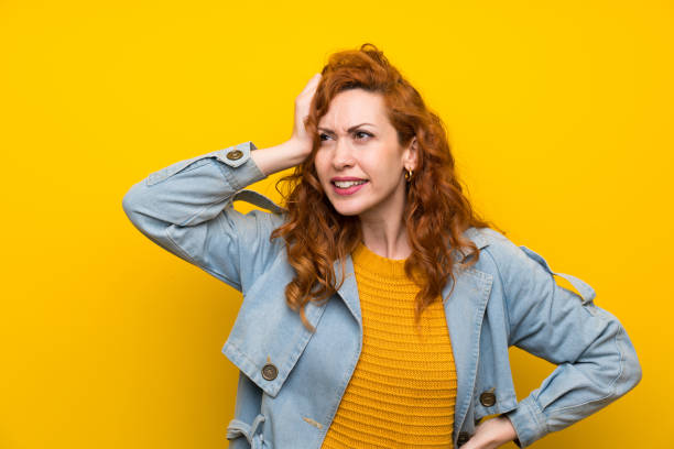 istock Redhead woman over isolated yellow background having doubts and with confuse face expression 1189550447